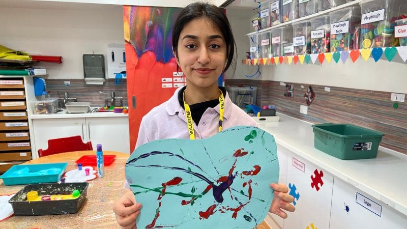 Ayeza, care team volunteer Ayeza, a care team volunteer at Helen & Douglas House hospice, is holding up a marble art painting.