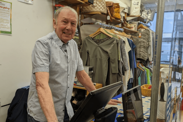 Peter smiling behind the till at a Helen & Douglas shop