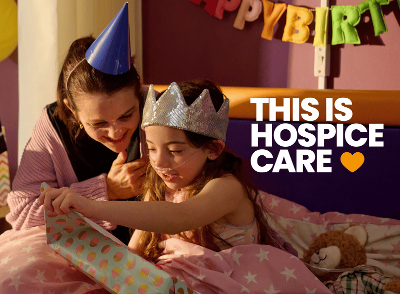 A young girl opening a birthday present with her mum