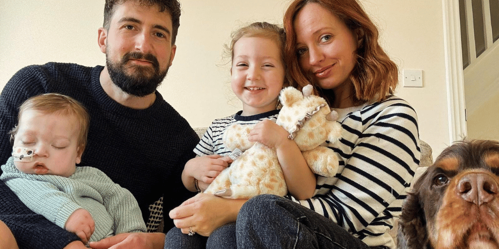 A photo of a man, woman, baby boy, little girl and a dog smiling.