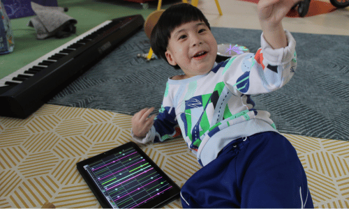 A young boy smiling and playing with an ipad