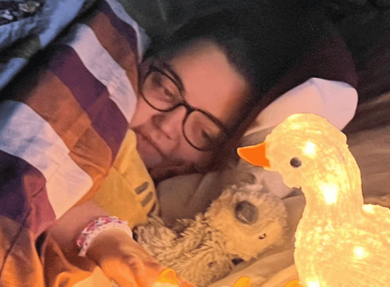 A young girl opening a birthday present with her mum