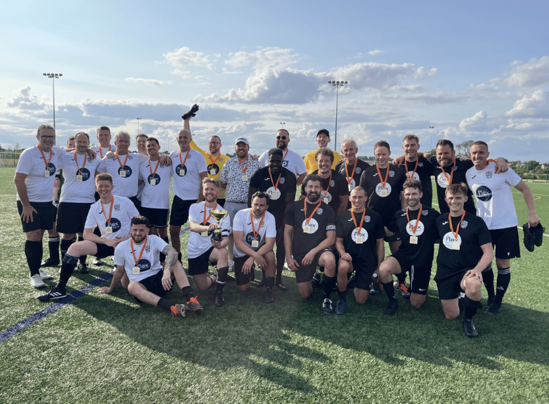A group of men wearing medals on a football pitch. 