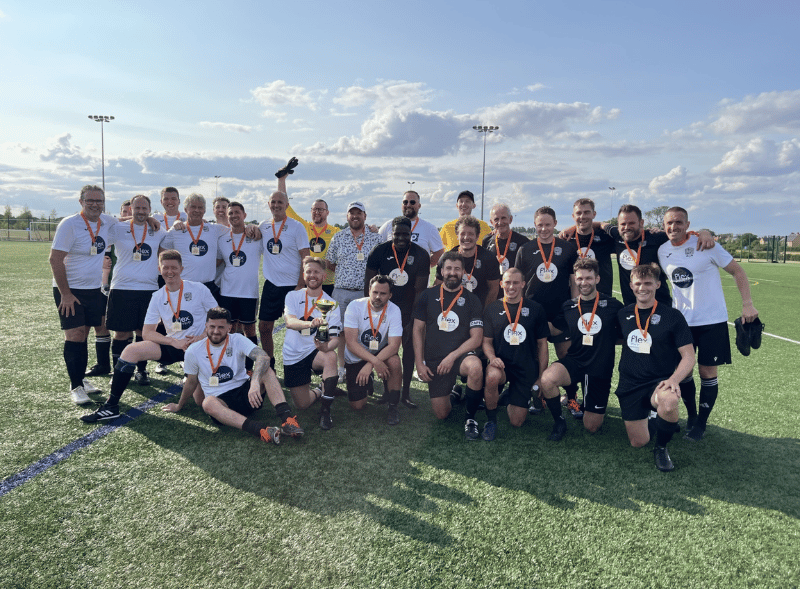 A group of men wearing medals on a football pitch.