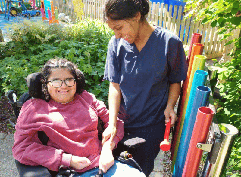 A young girl and a female nurse smiling in the sunny hospice garden