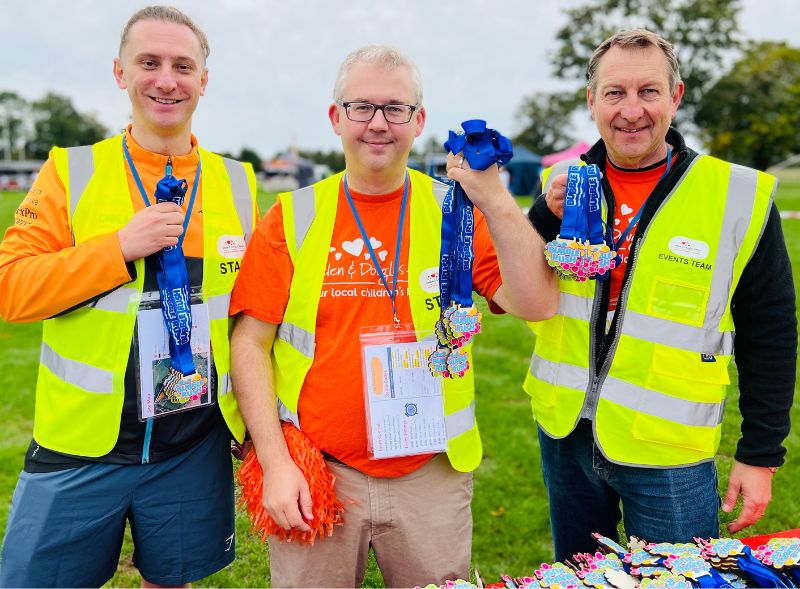 Three men smiling and holding bunches of Bubble Rush medals