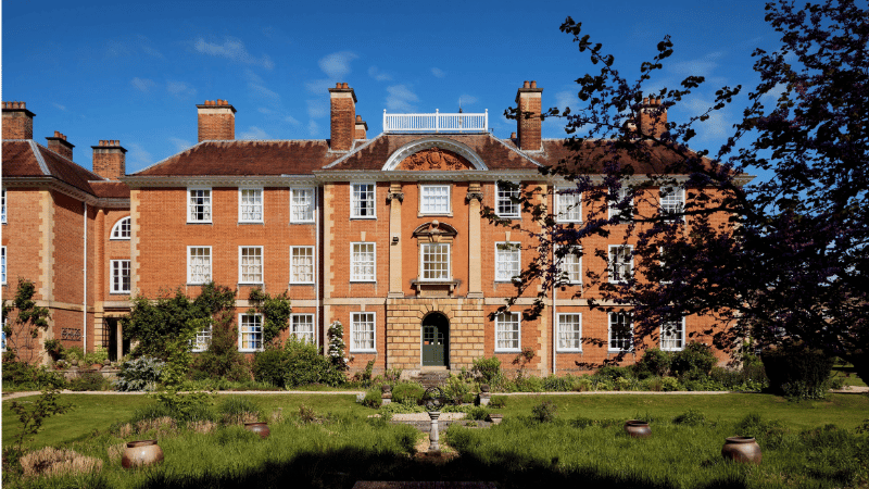 Lady Margaret Hall. A grand redbrick building with a green lawn in front of it.