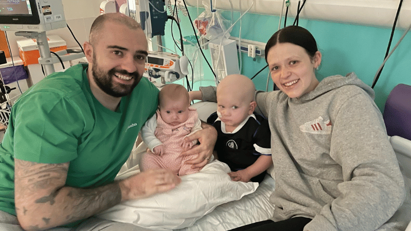 Calum, Betsy, Bobby and Faith sitting together in Bobby's hospital bed.