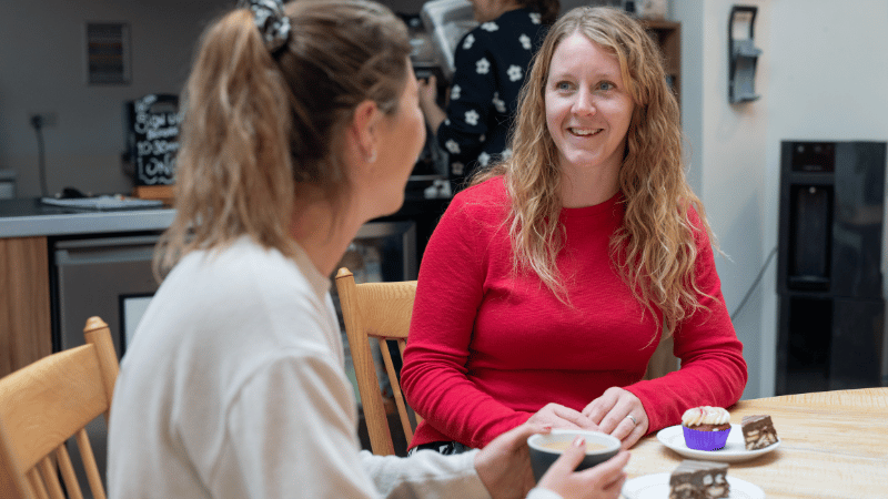 Rian talking to parent stock image Rhian, a nurse, talking to a woman at a table with tea and cake